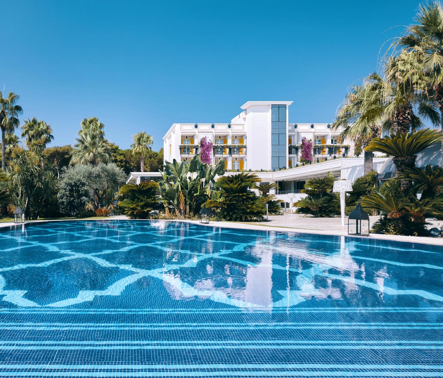 Hôtel de luxe avec piscine panoramique, entouré de verdure tropicale, avec une élégante architecture blanche et une atmosphère exclusive.