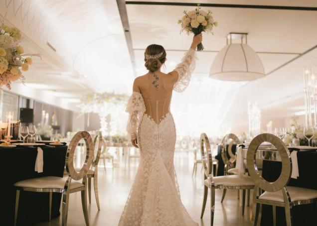 Mariée vêtue d'une robe sirène en dentelle avec un bouquet de fleurs, lors d'une élégante réception de mariage.