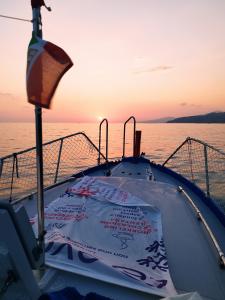 Barca in mare al tramonto, con vista sul sole che cala all’orizzonte.