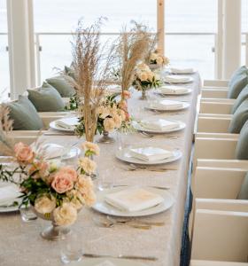Élégante décoration de table avec un centre de table floral et une vue panoramique sur la mer.