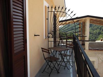 Balcony with wooden table and chairs, wrought iron railing and panoramic view of the green hills.