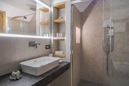 Bagno moderno con lavabo d’appoggio, specchio retroilluminato, doccia walk-in con rivestimento effetto pietra e nicchie in legno.