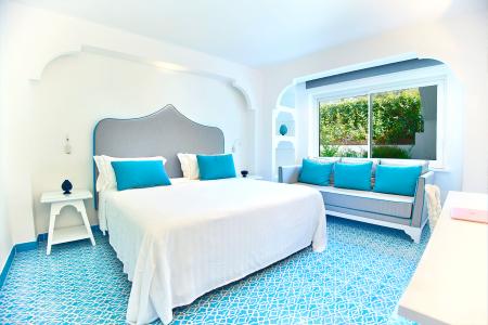 Bright bedroom with a double bed, gray headboard, turquoise accents, and decorative flooring.