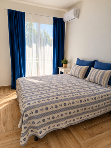 Bright bedroom with double bed, blue and white curtains and nautical-style linens.