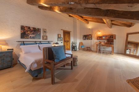Chambre à coucher de style rustique avec poutres apparentes en bois, parquet en chêne, mobilier artisanal et détails vintage.