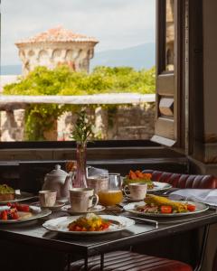 Petit-déjeuner gastronomique servi à table dans un cadre élégant, composé de mets sucrés et salés, avec vue sur un magnifique paysage dominé par une tour en pierre.