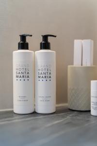 Dispenser da bagno Grand Hotel Santa Maria con balsamo e sapone liquido, accessori da toilette e prodotti per la cura del corpo in un elegante ambiente alberghiero.
