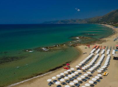 Golden sandy beach with white umbrellas and crystal-clear turquoise sea.