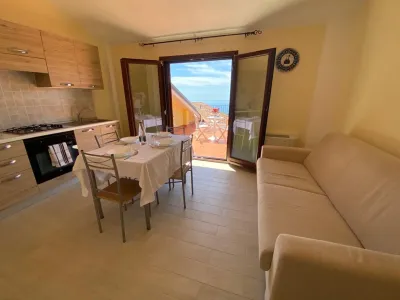 Junior Suite mit voll ausgestatteter Küche, Essbereich, Sofa und Terrasse mit Meerblick.