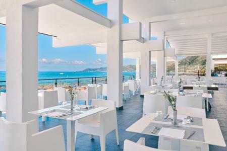 Panoramic terrace overlooking the sea with set tables and views of the coast.