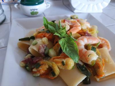 Piatto di pasta con gamberi, verdure e basilico fresco.