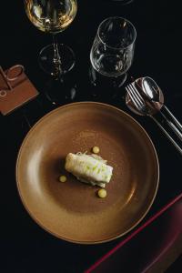 Gourmet dish presented on handcrafted ceramic tableware, with wine glasses and cutlery on a black table, in an elegant and refined atmosphere.