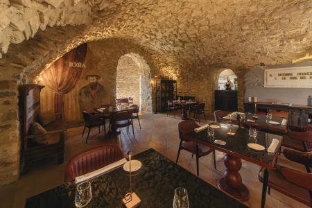 Elegant restaurant in an ancient stone hall with vaulted ceilings, refined table settings and warm lighting.