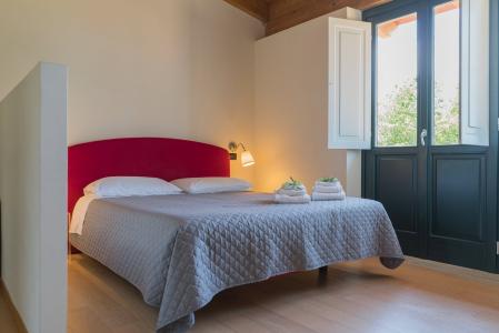 Bright double bedroom with red headboard and French door.