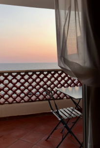 Sea-view balcony at sunset, with a table and chairs overlooking the horizon.