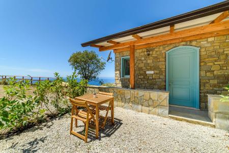 Outdoor area of the Enea Room with table and chairs, surrounded by nature and overlooking the sea.